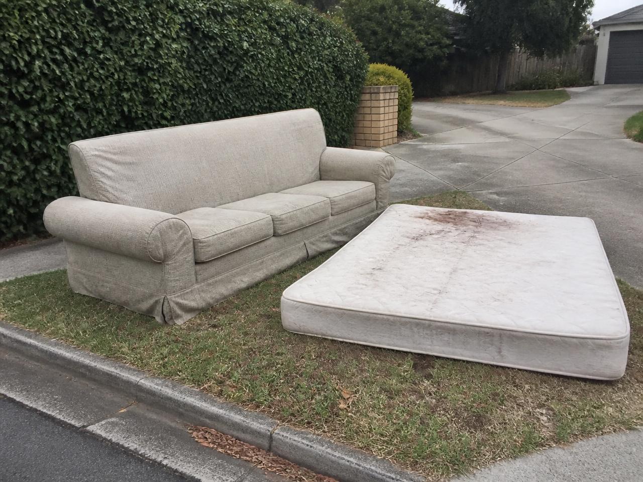 Old couch and stained mattress left on a suburban nature strip